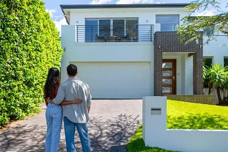 A couple standing in front of their first house that they bought with kiwisaver - listing