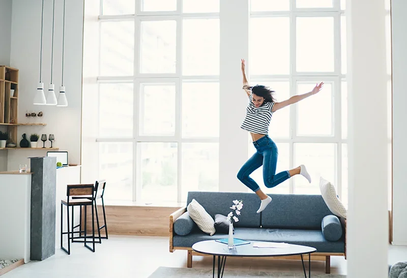 A woman jumping for joy on a couch