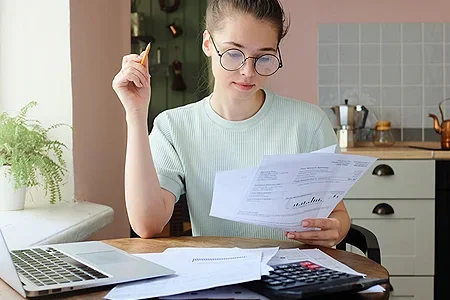 Student female doing some financial budgeting at dining table - listing