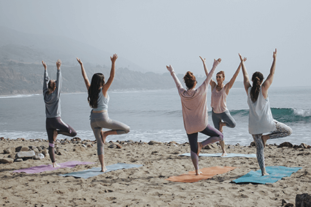 five-women-doing-yoga-on-the-beach